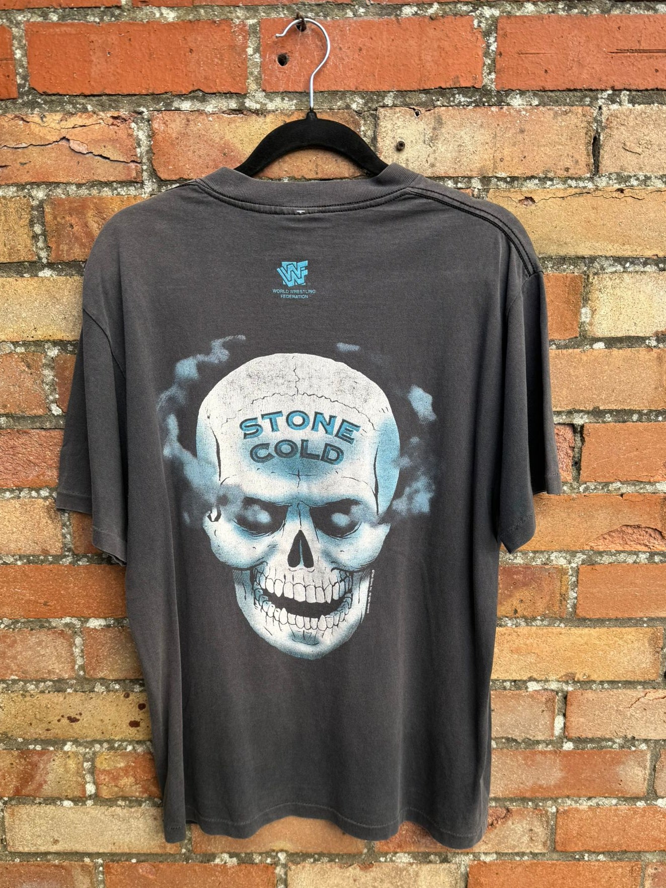 Back view of a black t-shirt with WWF branding and a Stone Cold skull