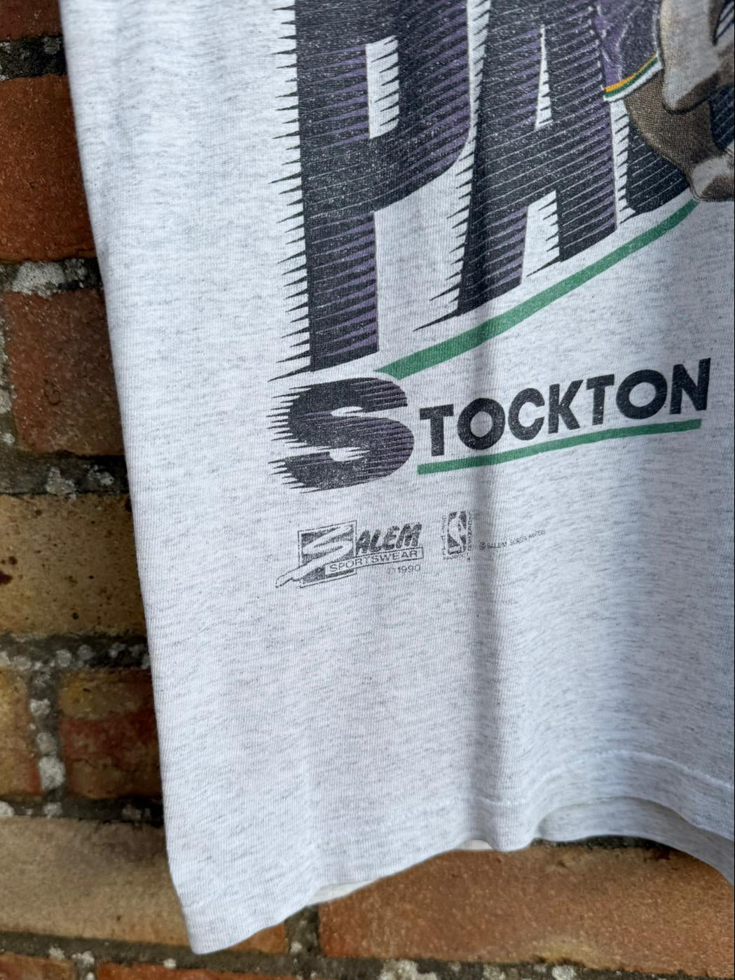 Gray t-shirt with Stockton name text and Salem Sportswear logo on a brick surface
