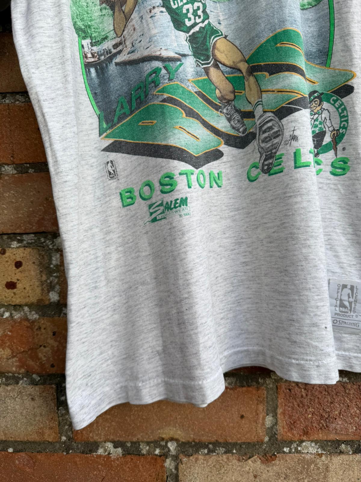 Gray t-shirt with Boston Celtics and Salem Sportswear logos and graphics on a brick wall background