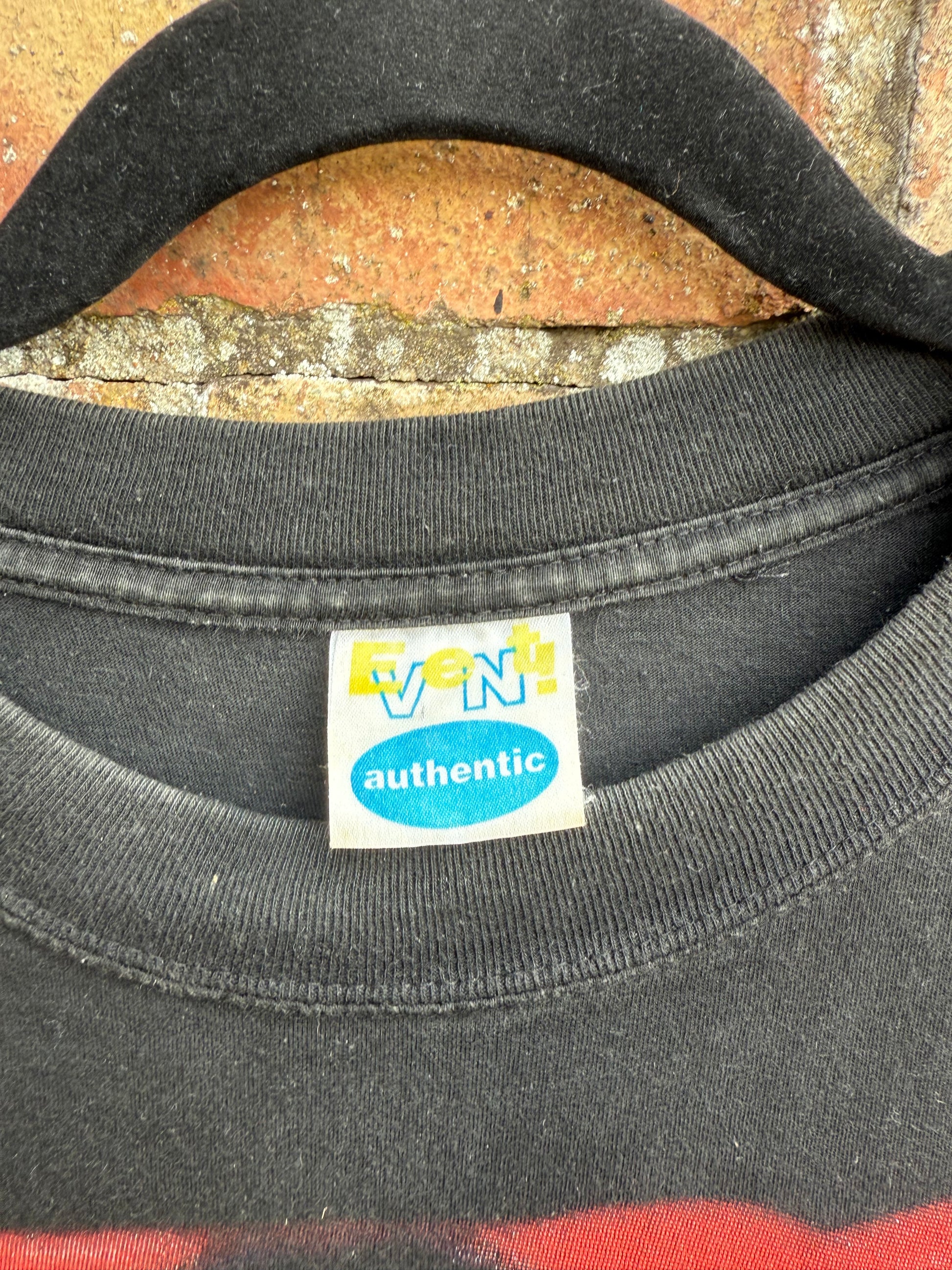 Close-up of a black t-shirt with an Event Authentic label on a textured surface