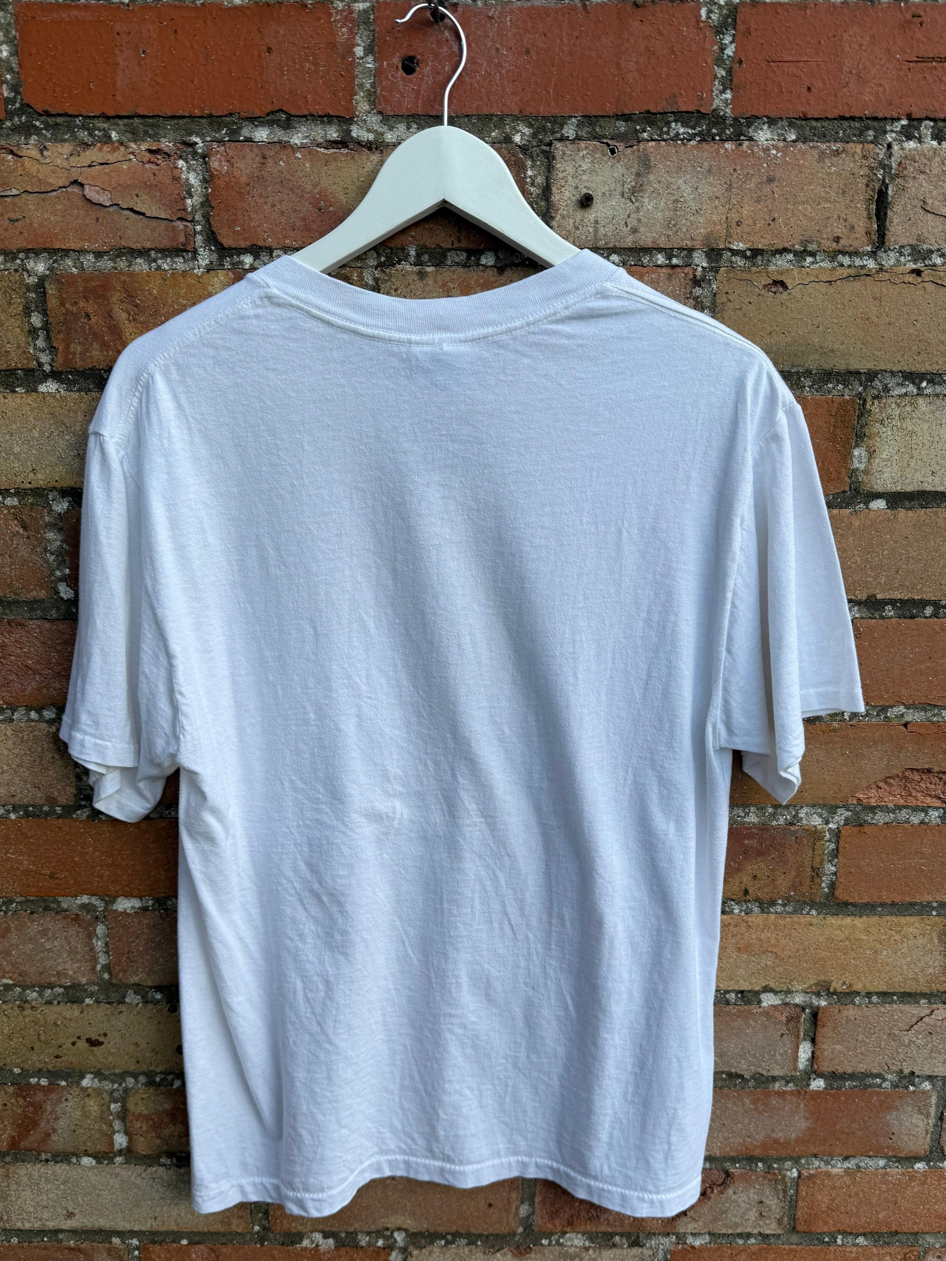 White t-shirt on a hanger against a brick wall
