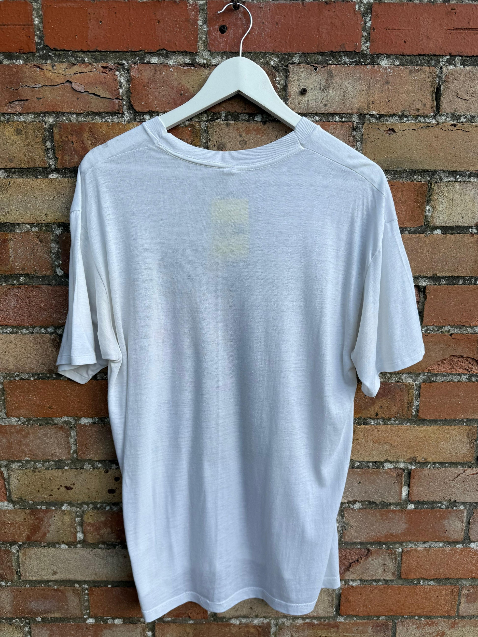 White t-shirt on a hanger against a brick wall