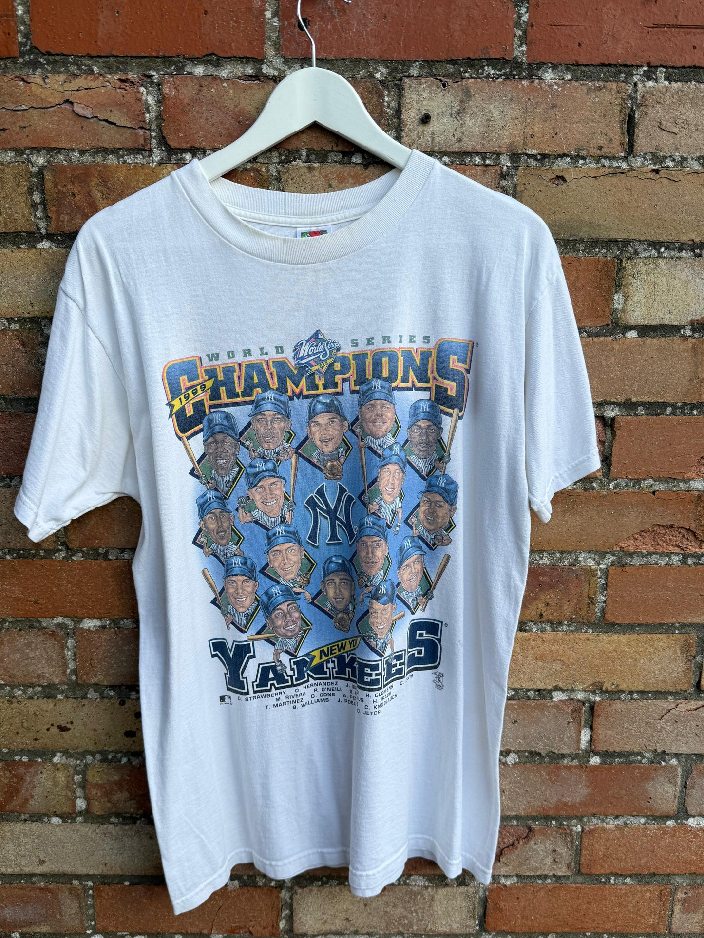 White t-shirt with New York Yankees World  Series Champions team, on a hanger against a brick wall