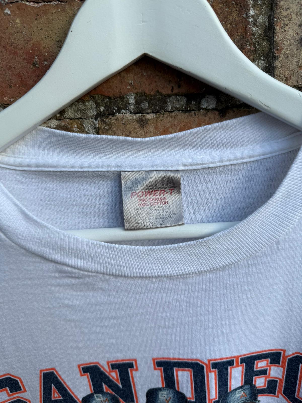 White t-shirt with 'San Diego' text and close-up of Oneita Power-T tag, on a hanger against a brick wall.