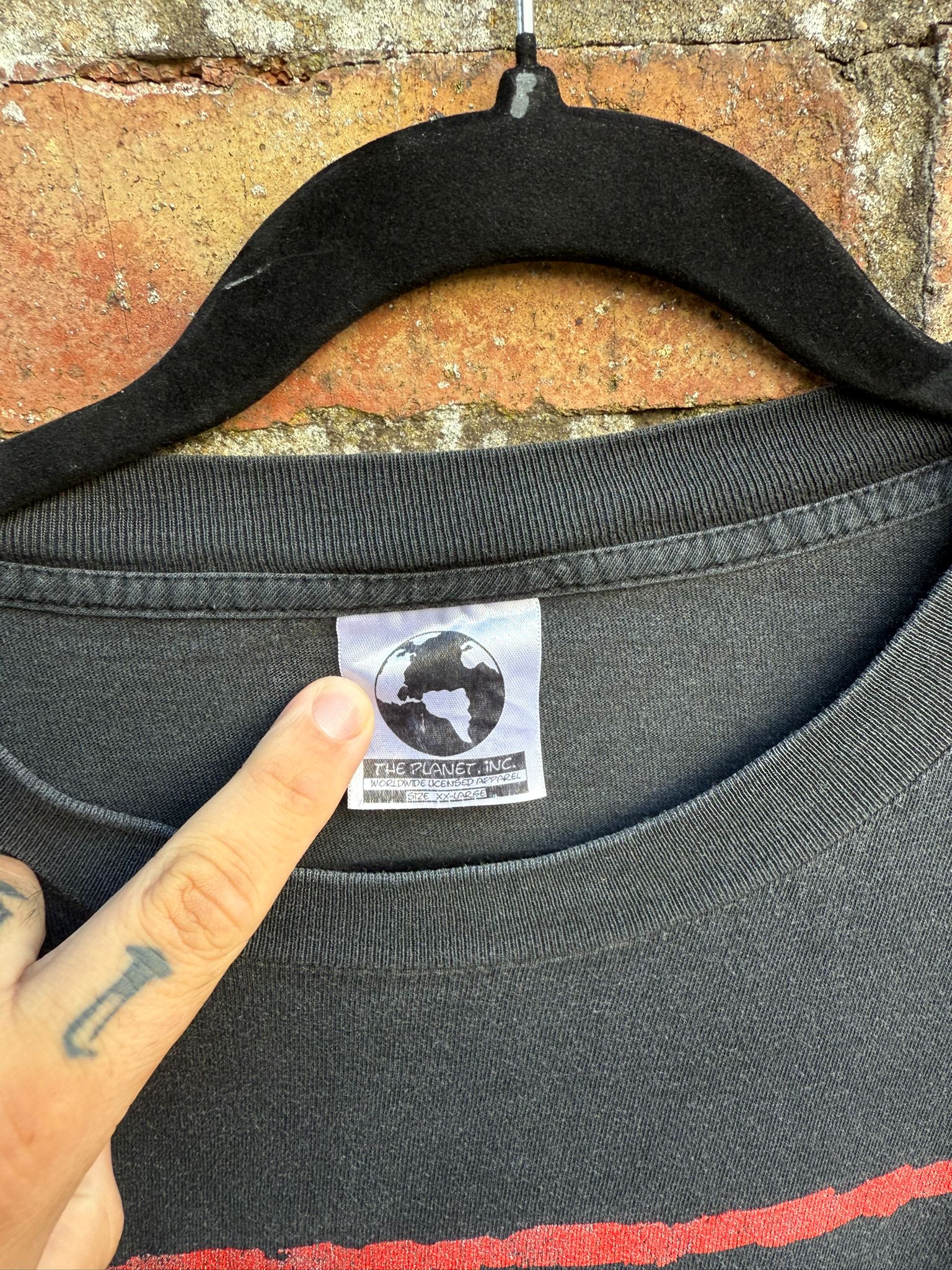 Black t-shirt with a brand label on a brick wall background