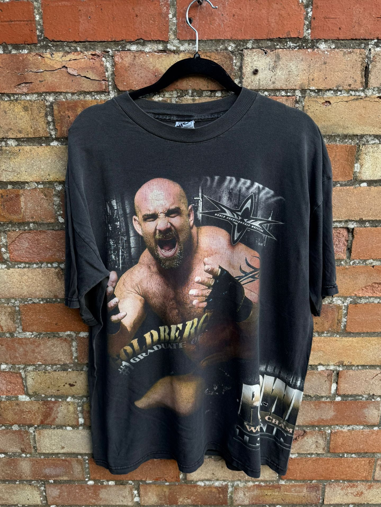 Black graphic t-shirt with wrestler Goldberg and printed phrases