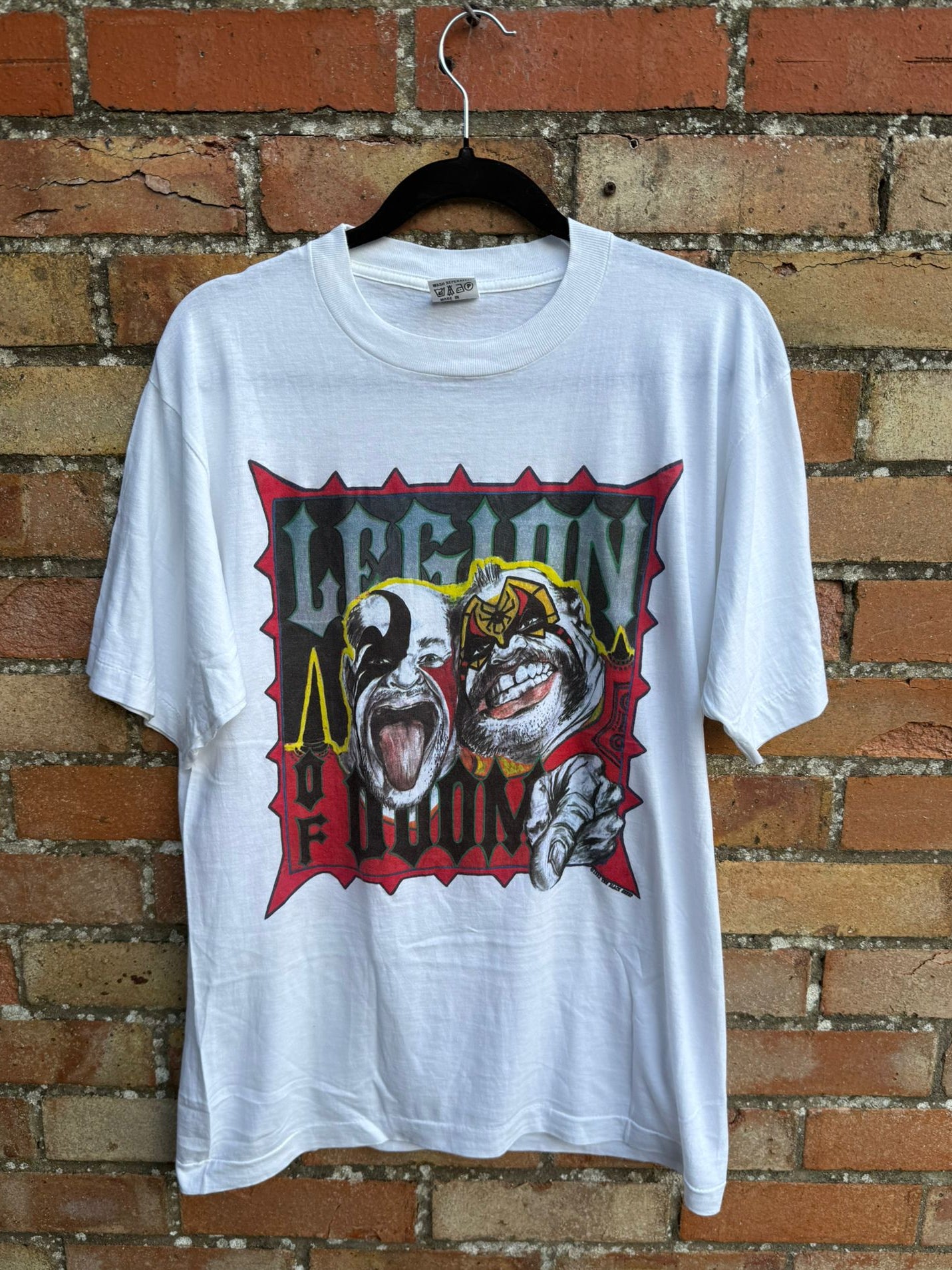 White t-shirt with graphic design and 'Legion of Doom' text on a brick wall background
