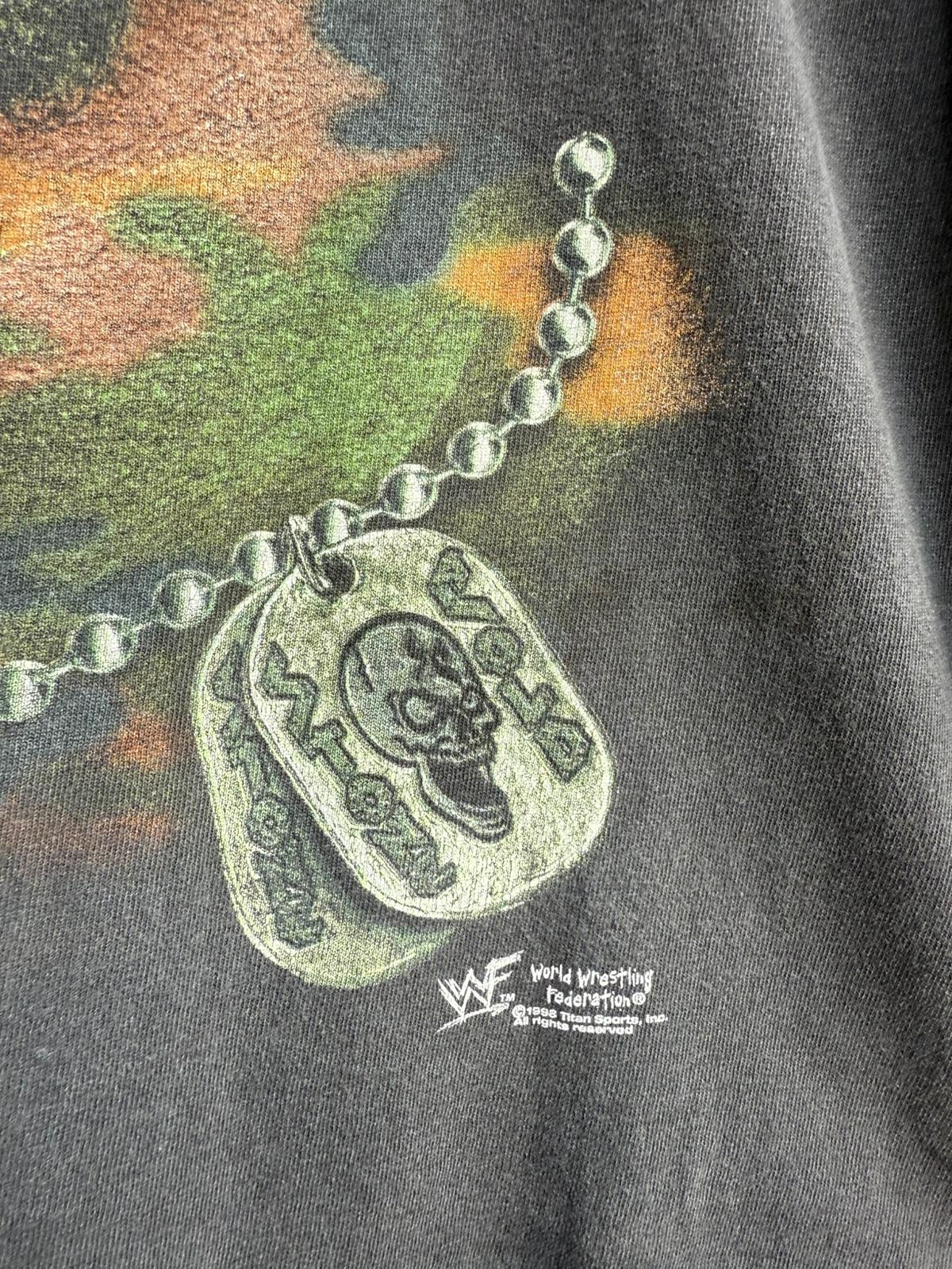 Close up of Metallic necklace with Stone Cold pendant and WWF branding on camouflage-patterned material