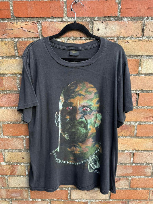 Black t-shirt with graphic design of a camouflaged face on a brick wall background