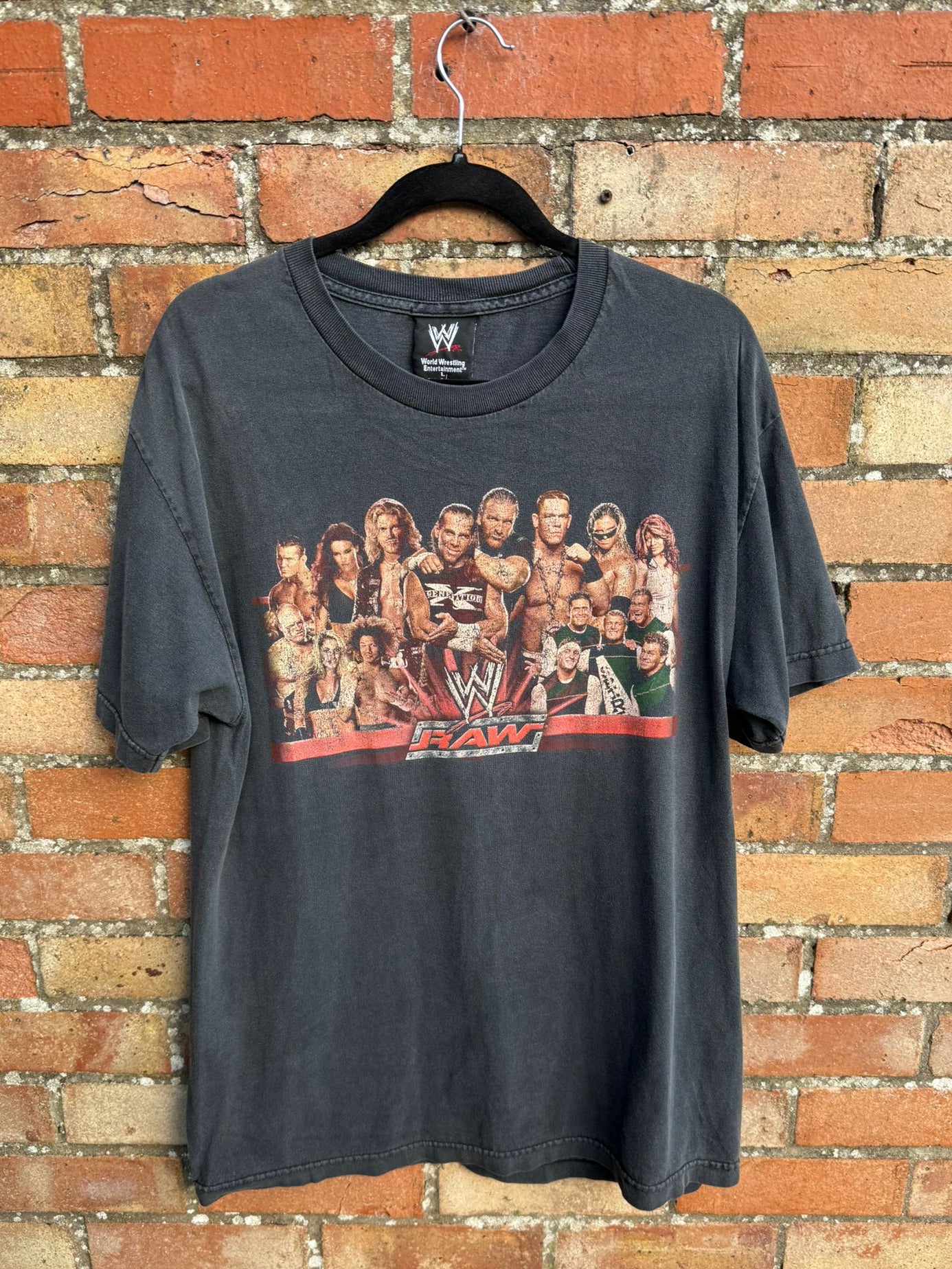 Black t-shirt with WWE graphic on its front and the word RAW