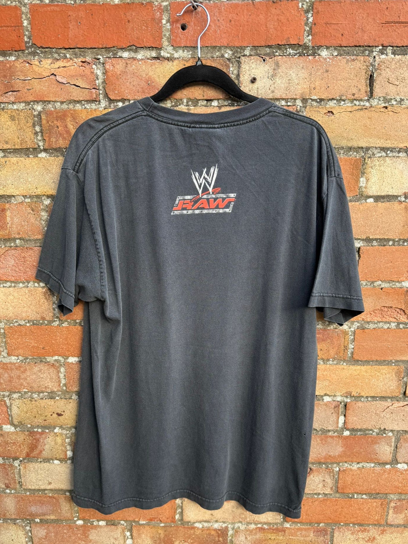 Reverse side of a black t-shirt featuring the WWE logo and RAW