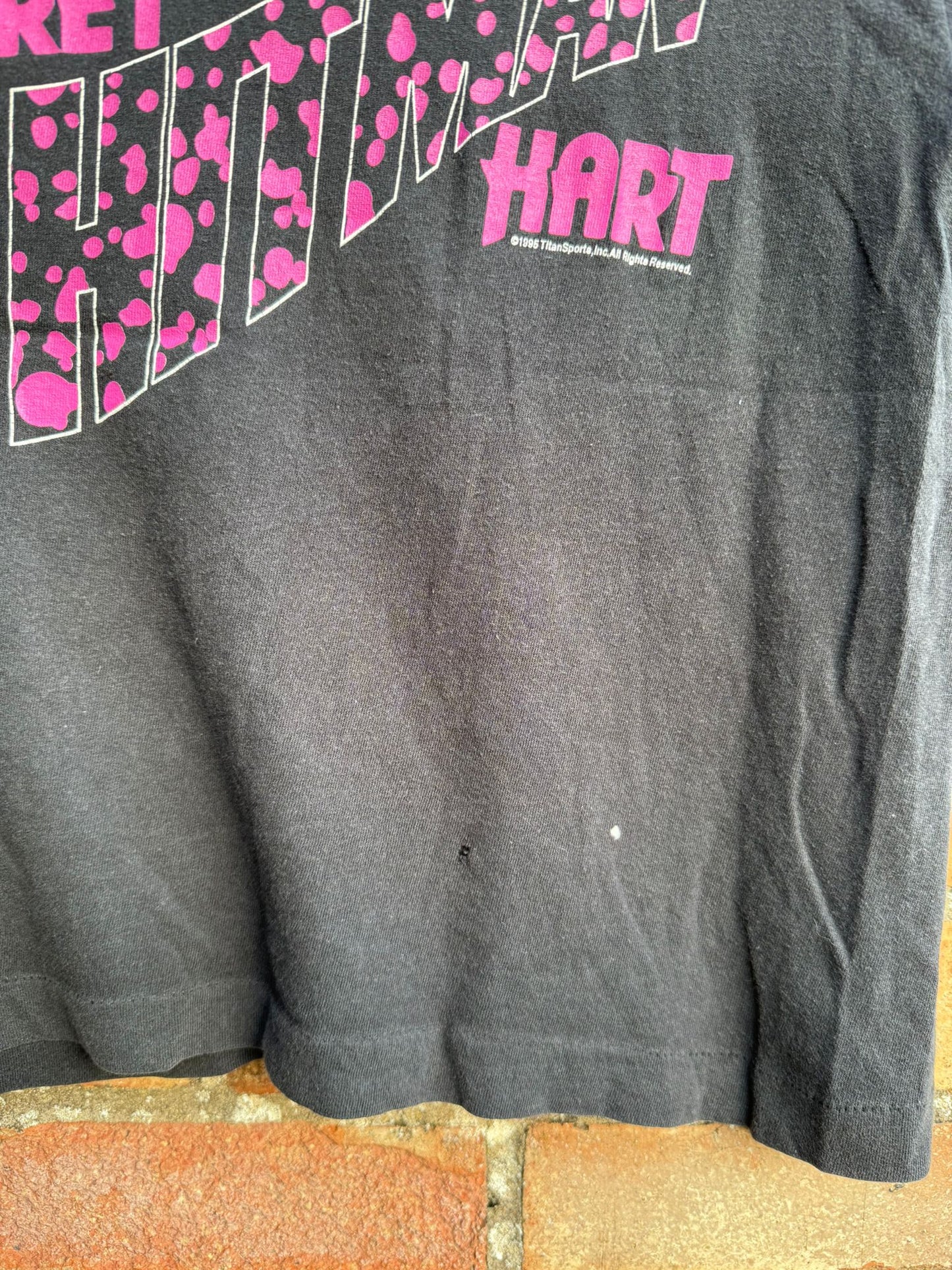 Bottom edge of black wrestling t-shirt showing a small bleach mark