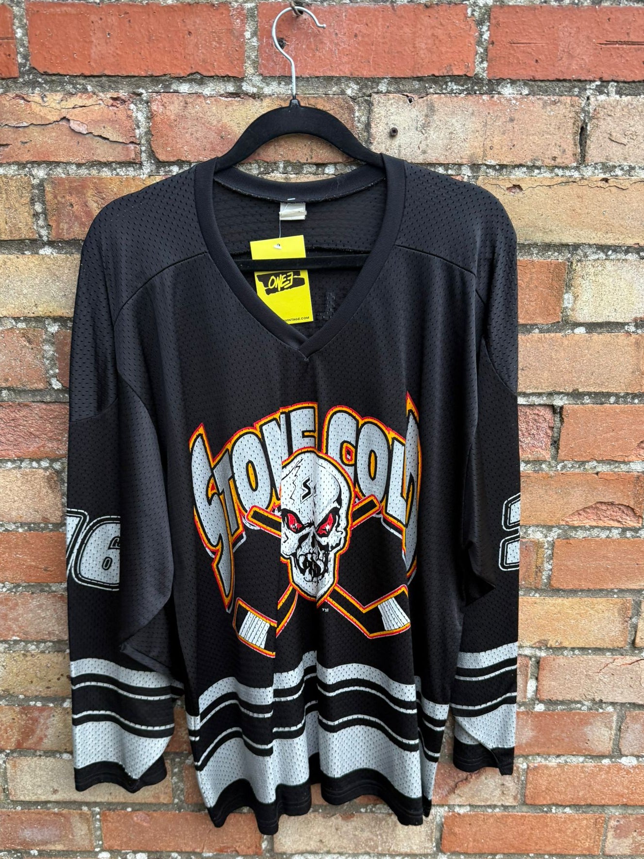 Black sports jersey with a skull design and 'Stone Cold' text on a brick wall background