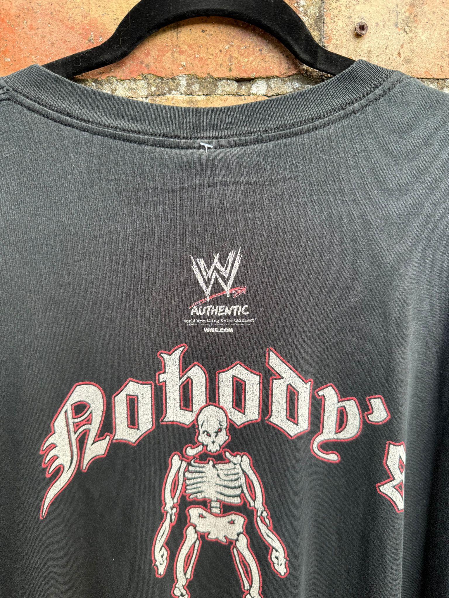 Black t-shirt with WWE logo and skeleton design on a textured surface