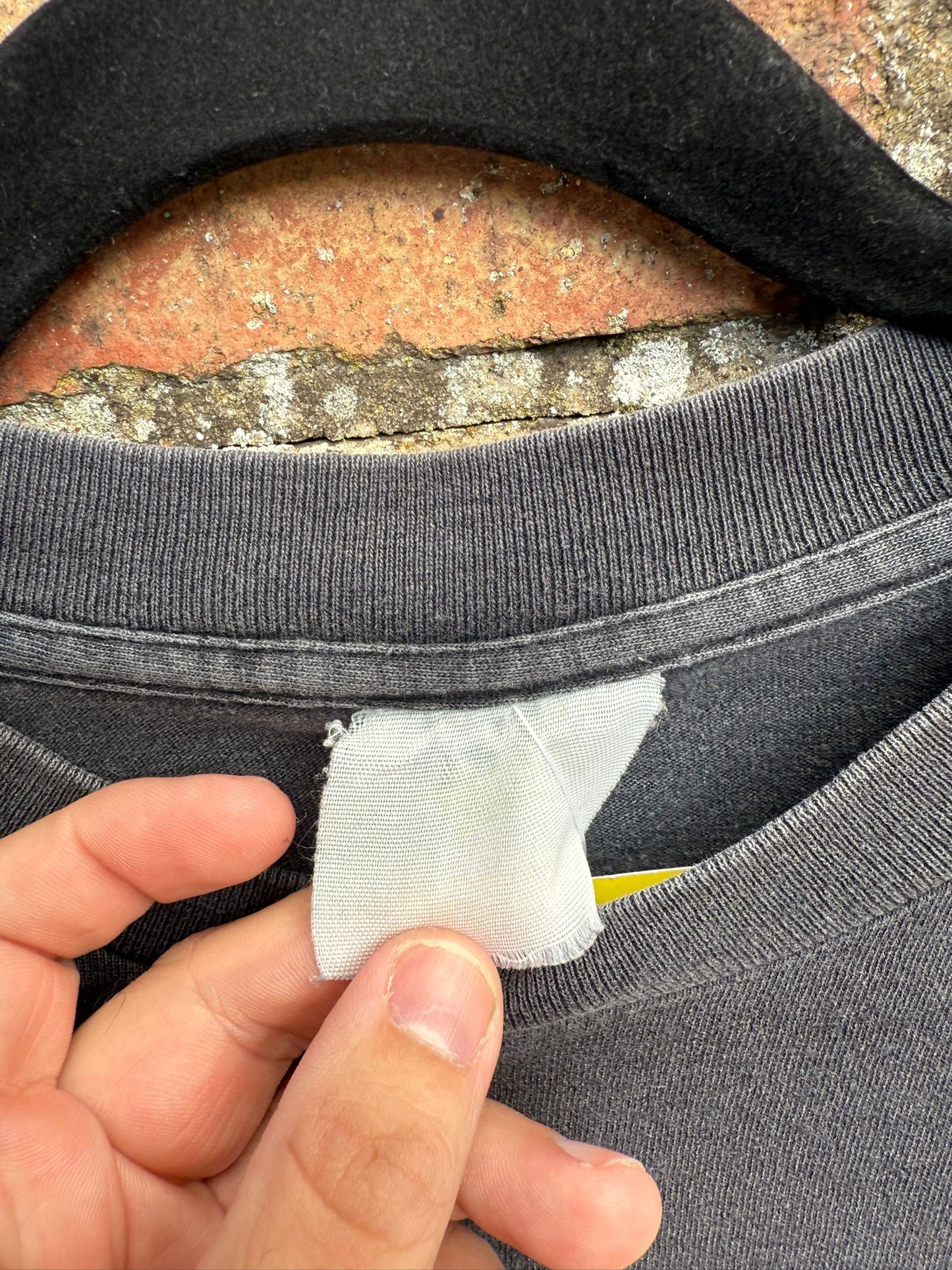 Close-up of a washed out tag on a black garment held by a hand.
