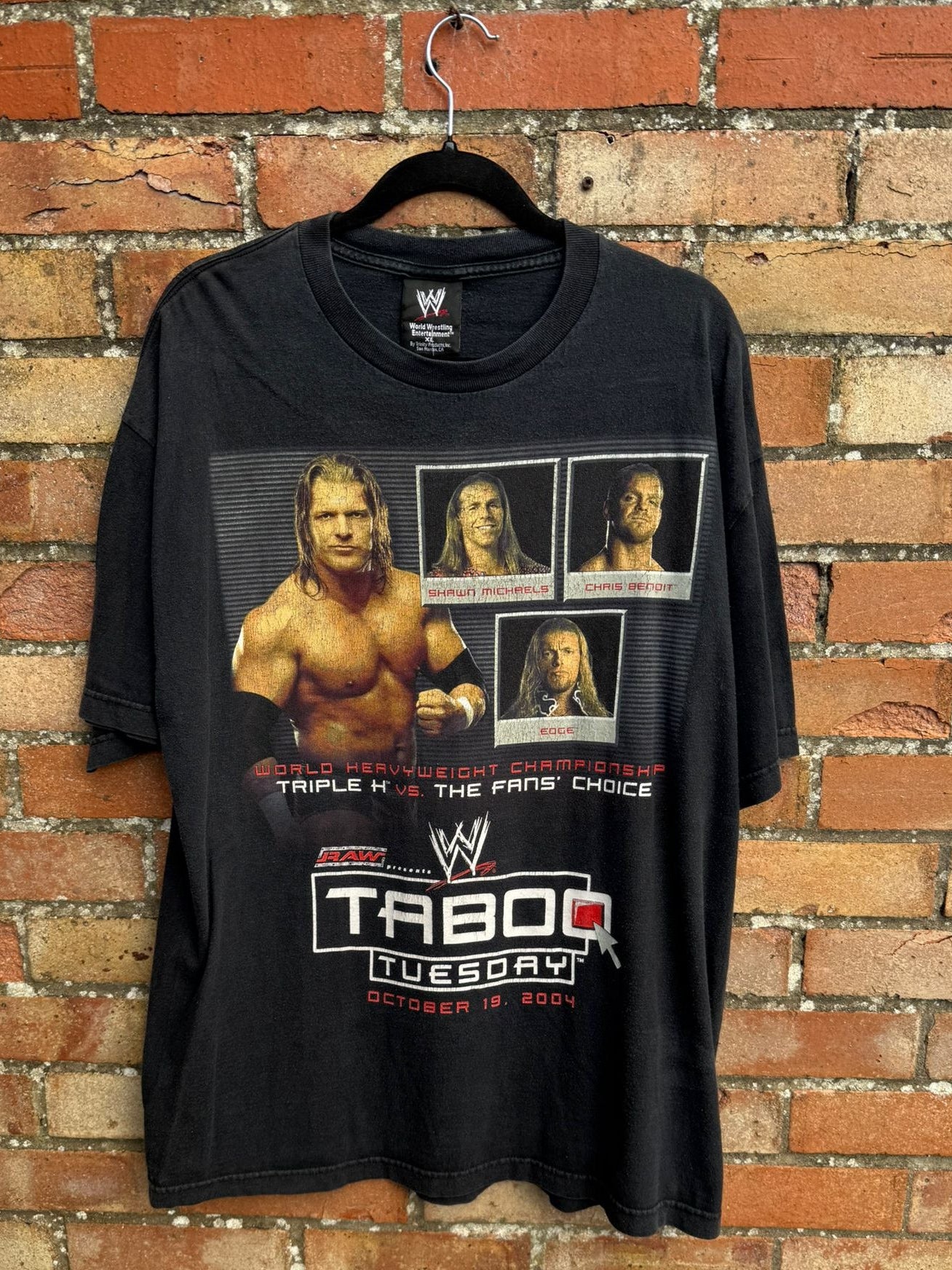 Black t-shirt with WWE graphics and Taboo Tuesday text on a brick wall background