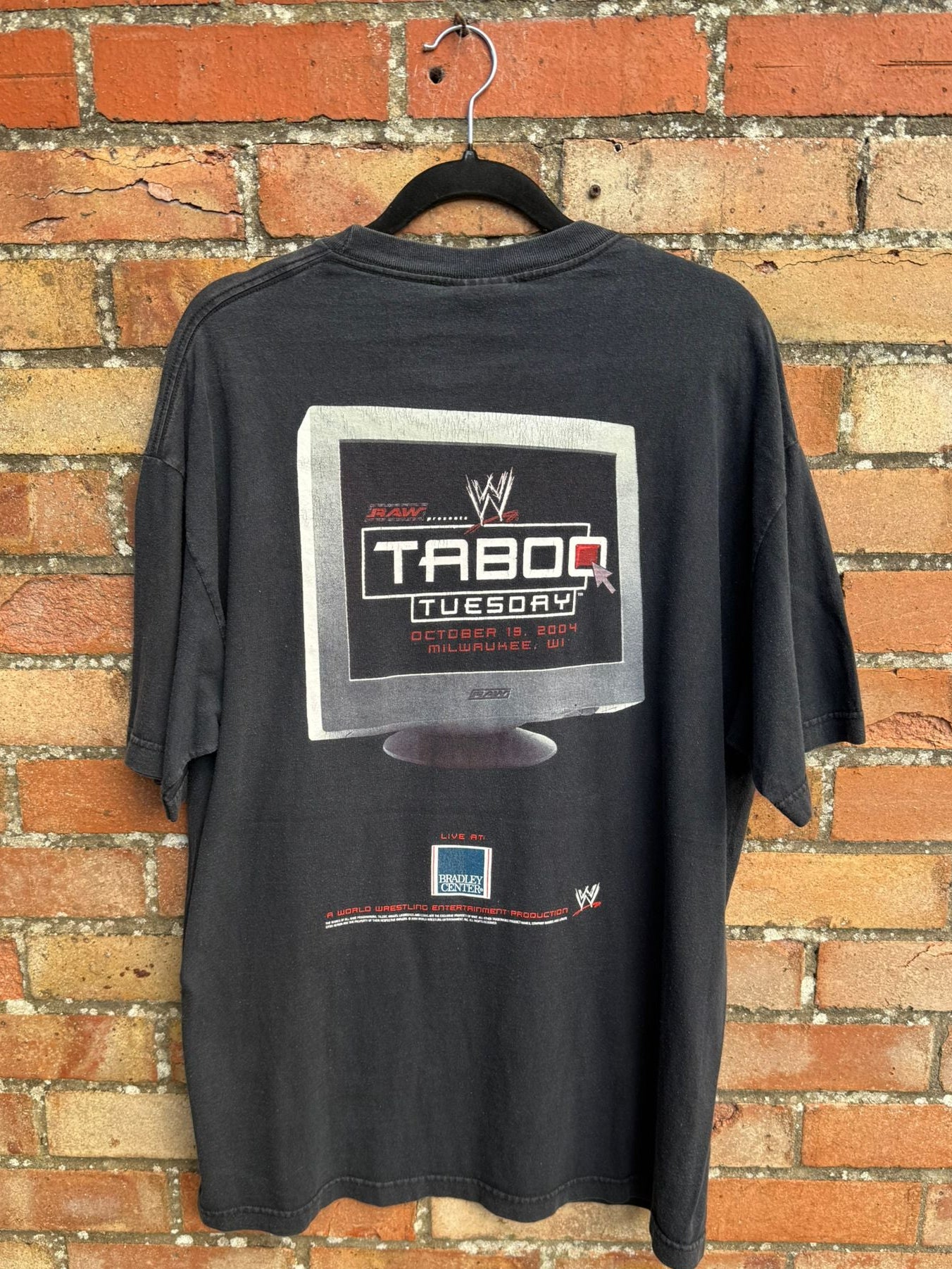 Black t-shirt with TV graphic and Taboo Tuesday text on a brick wall background