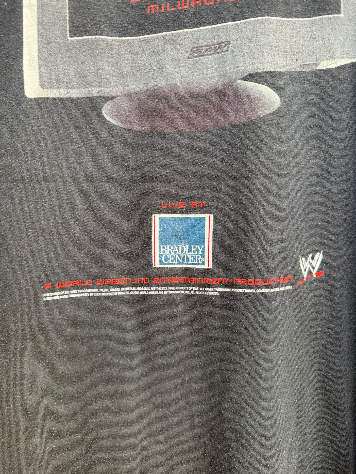 Black t-shirt close-up with wrestling event details and WWE logo on a dark background