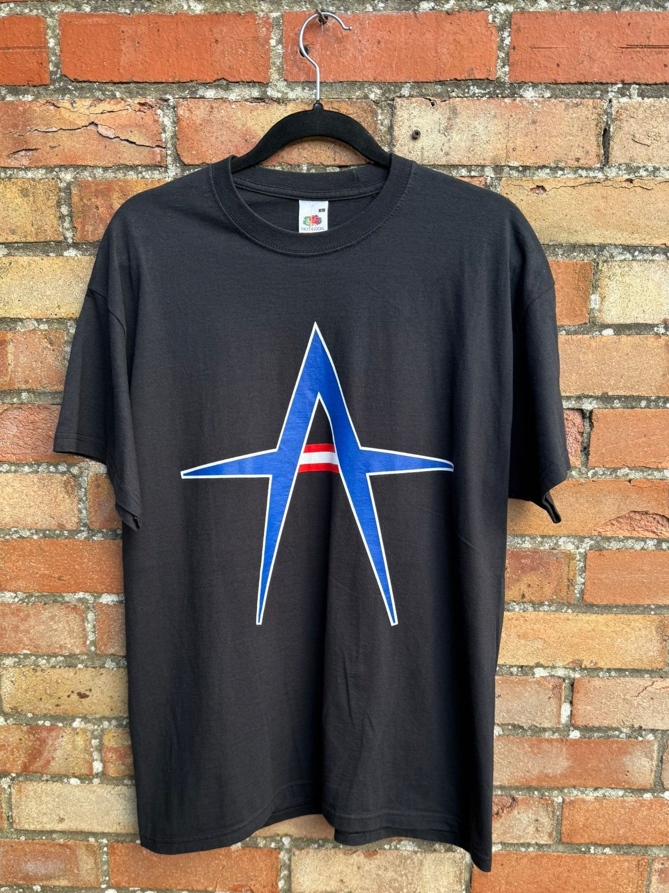 Black t-shirt with a Kurt Angle blue design on a brick wall background