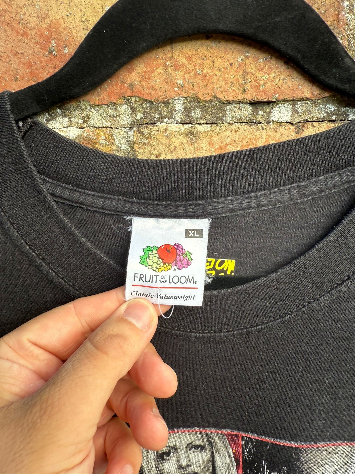 Black t-shirt with a visible Fruit of the Loom label on a textured surface.