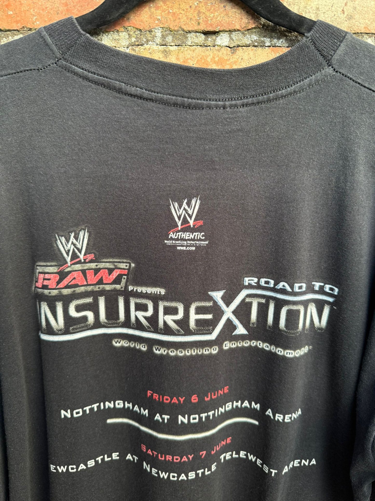 Black sweatshirt with WWE branding and Road to Insurrextion text on a brick wall background