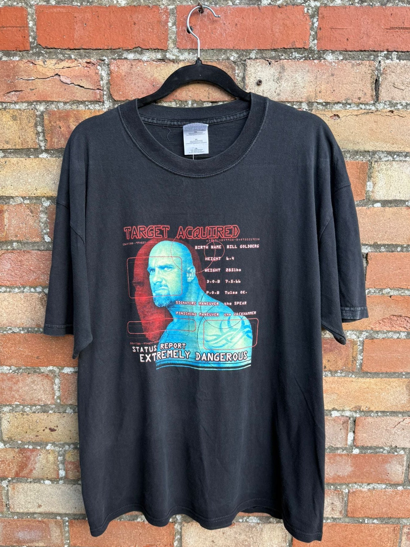 Black t-shirt with graphic design on a hanger against a brick wall