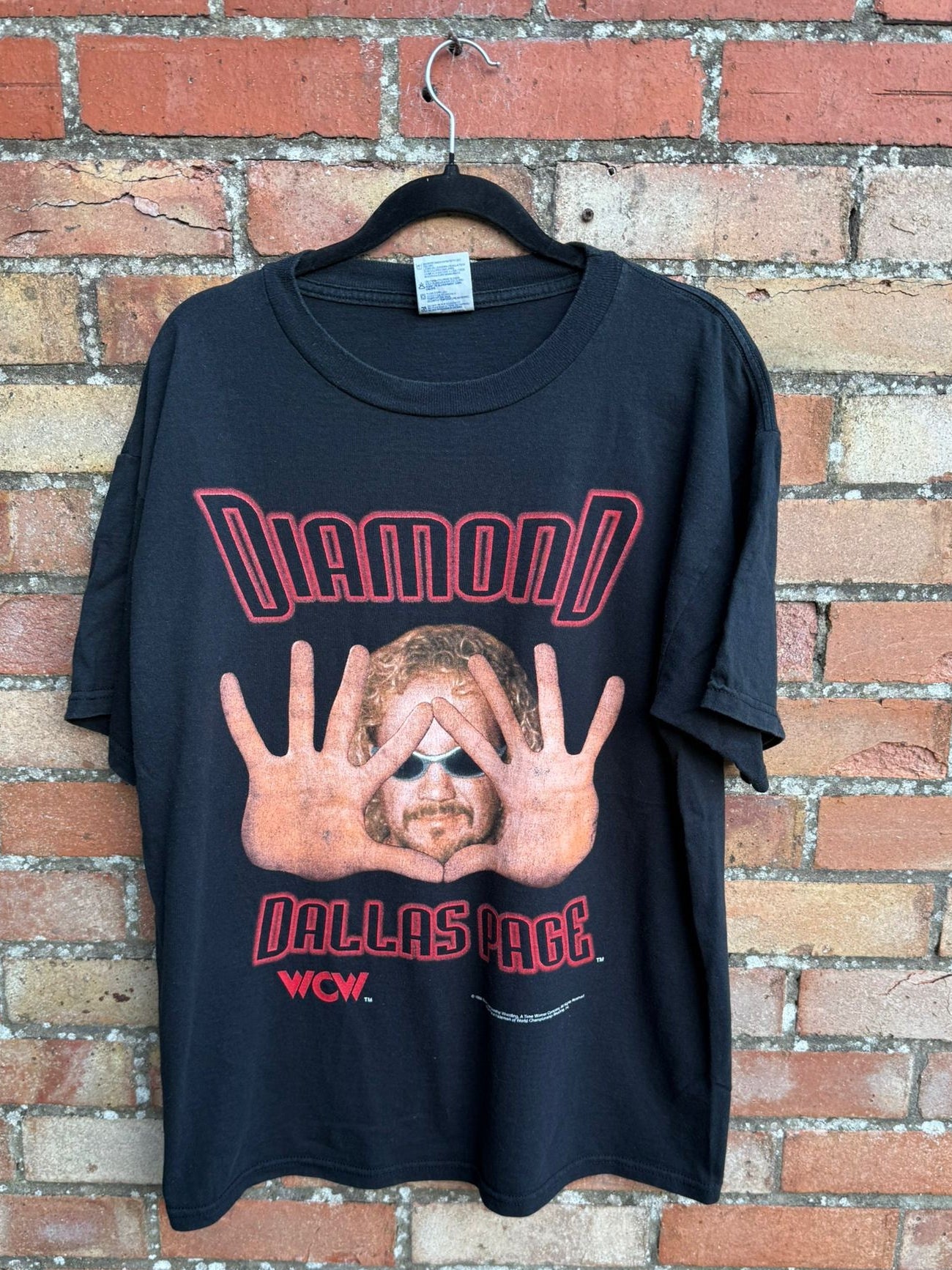 Black t-shirt with graphic design and text showing Diamond Dallas Page against a brick wall background