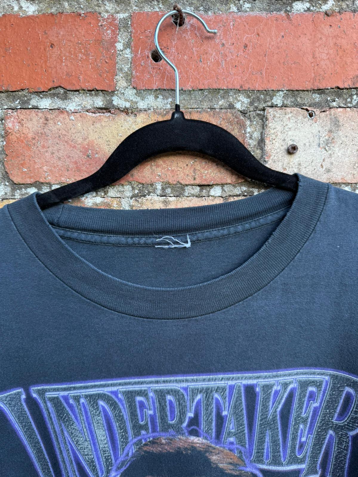 Close-up of black t-shirt with Undertaker text showing a missing clothes tag