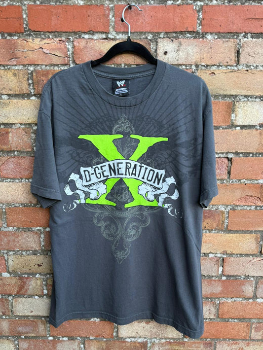 Gray t-shirt with green and white D-Generation X graphic design on a hanger against a brick wall.