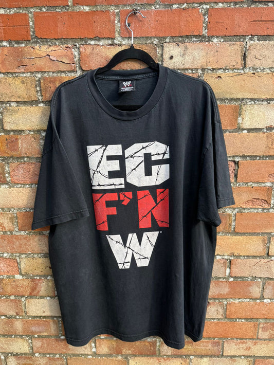 Black t-shirt with graphic text EC F'N W on a hanger against a brick wall