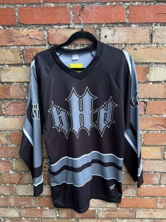 Black sports jersey with WWF Triple H logo on a hanger against a brick wall