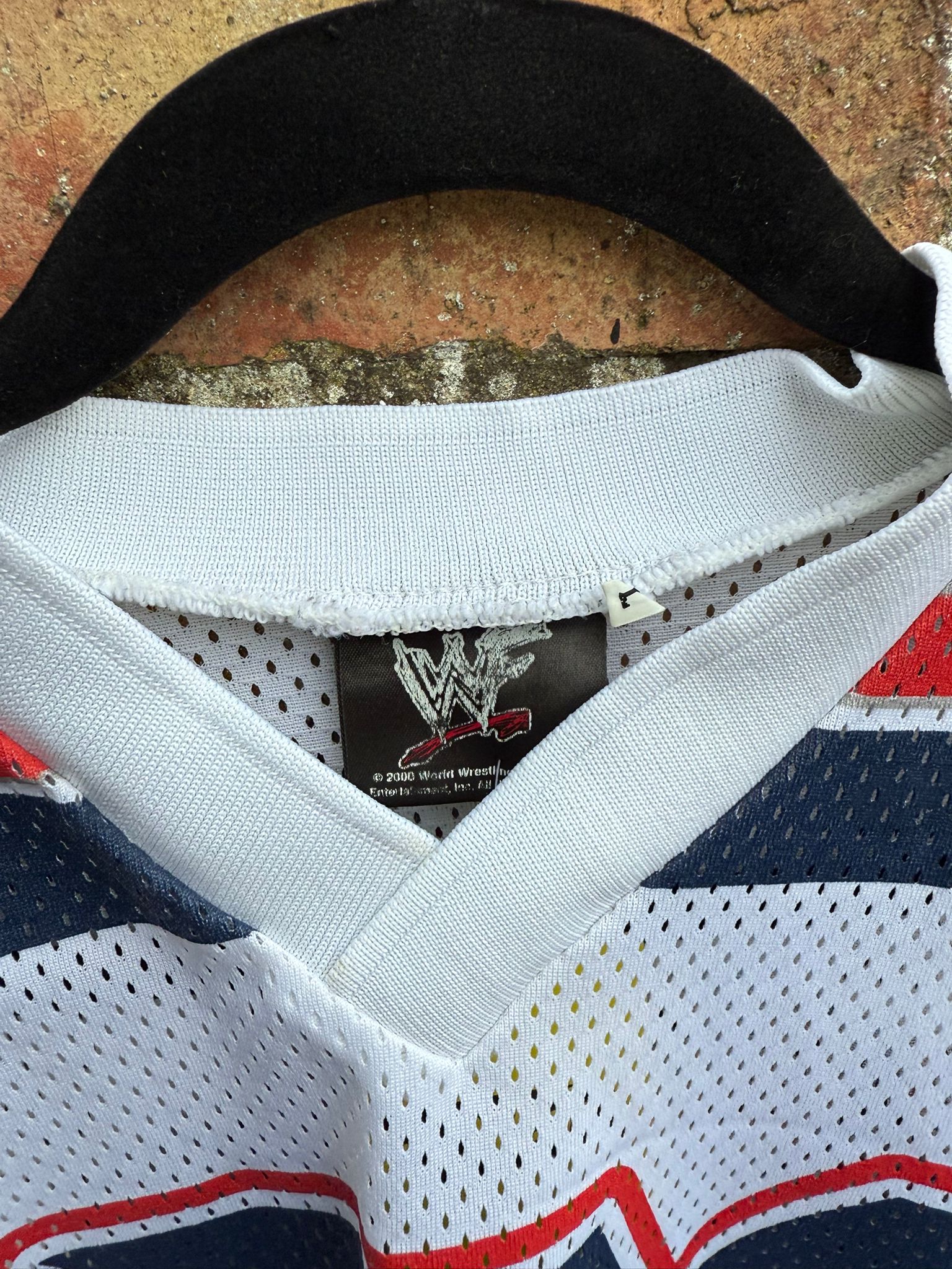 Close-up of a sports jersey with a WWE brand label on a textured surface